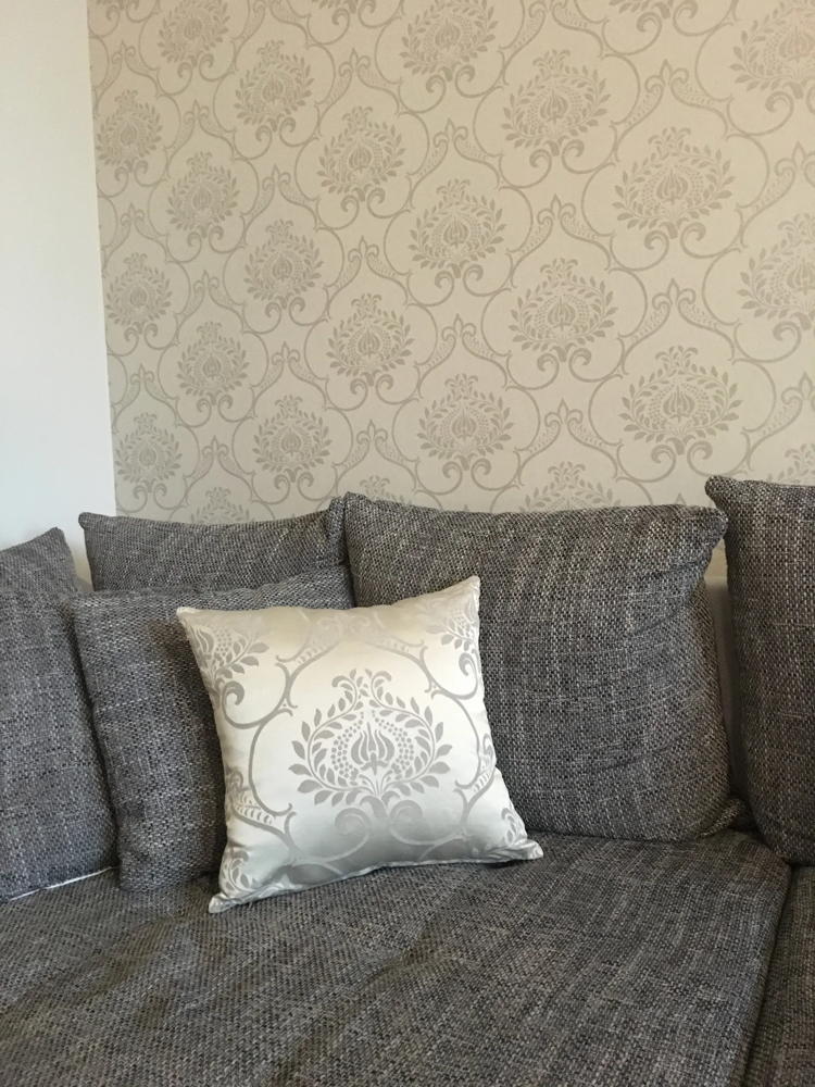 Sofaecke mit weißem Kissen vor Mustertapete