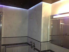 Weiße Wand mit Marmorimitation und lila Hintergrundbeleuchtung