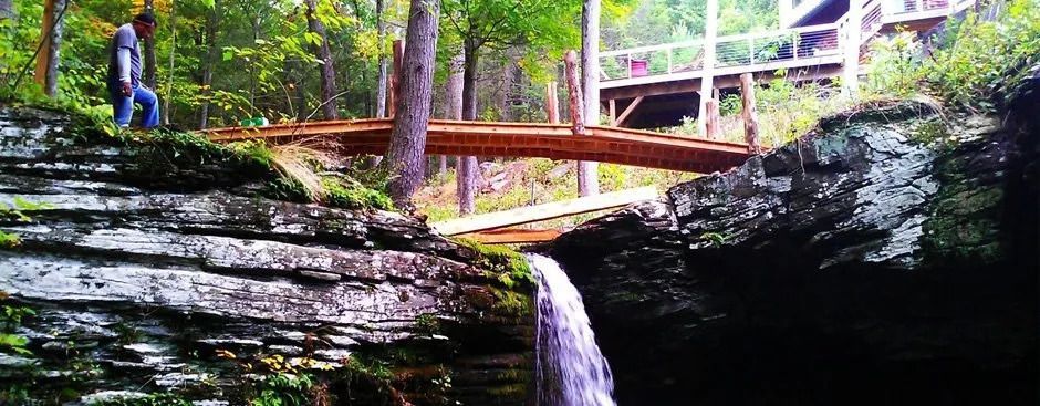 Men building a bridge over a waterfall — Newburgh, NY — Benjamin & Sons Landscaping