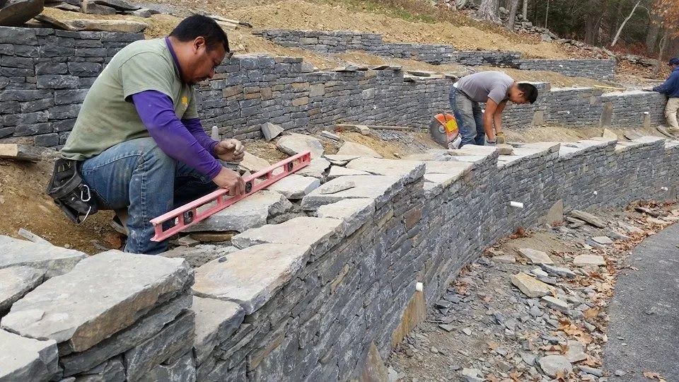 A person using a level to make a stone wall — Newburgh, NY — Benjamin & Sons Landscaping