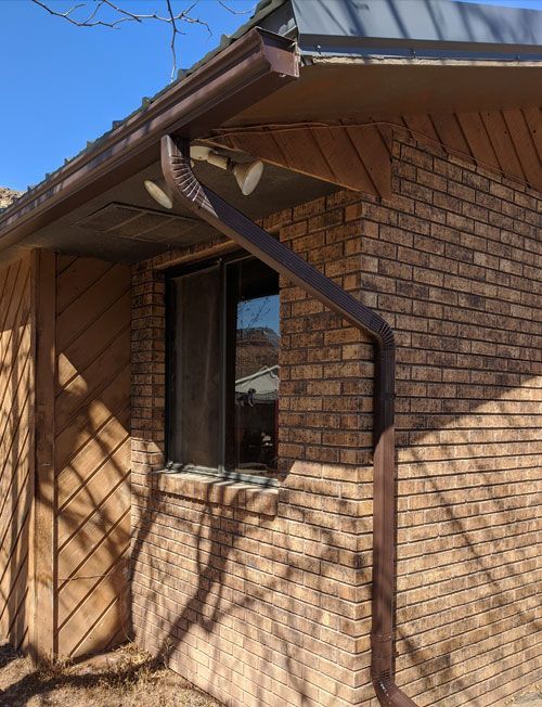 A brick building with a window and a gutter on the side.