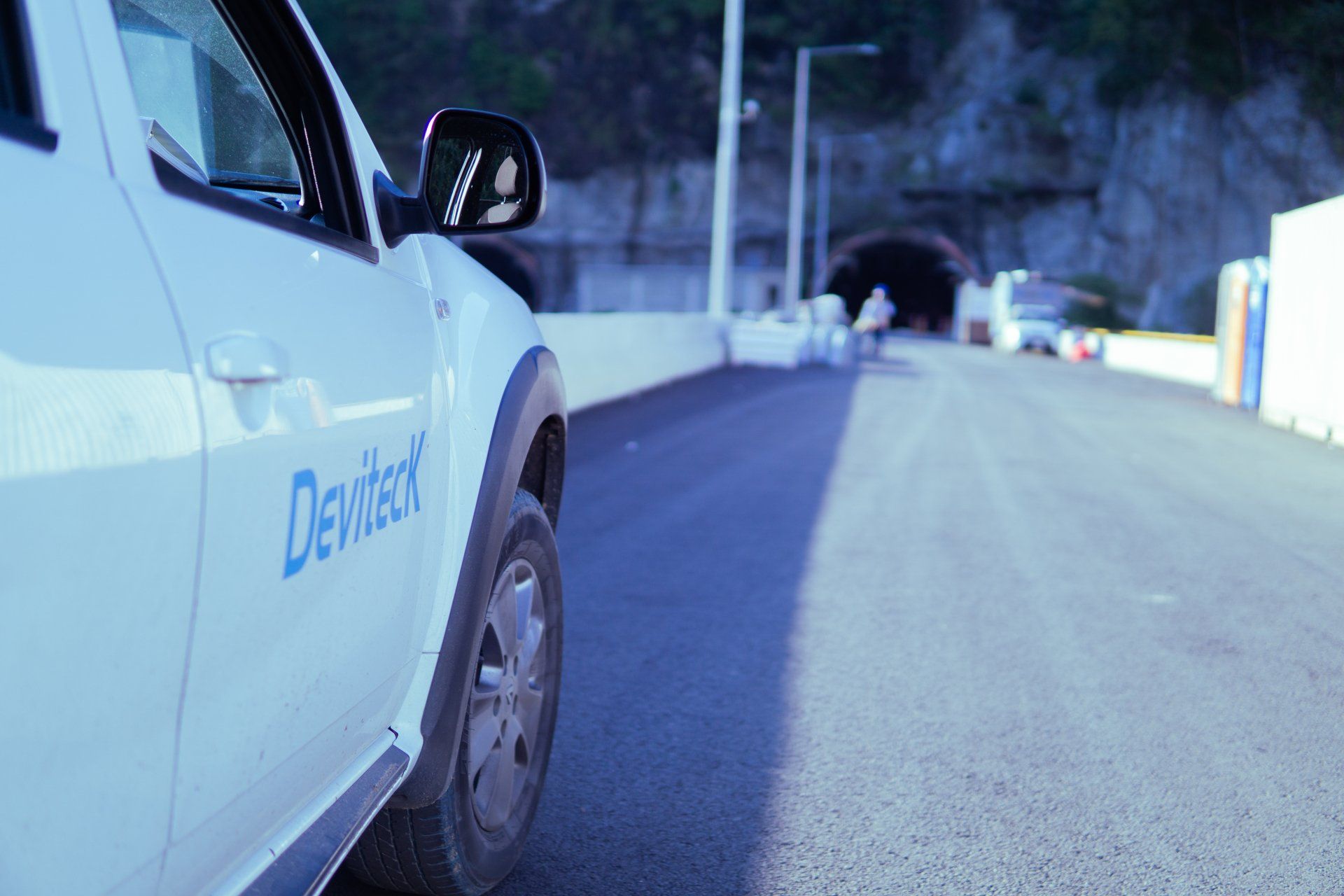 Un coche blanco está aparcado al costado de una carretera al lado de un túnel.
