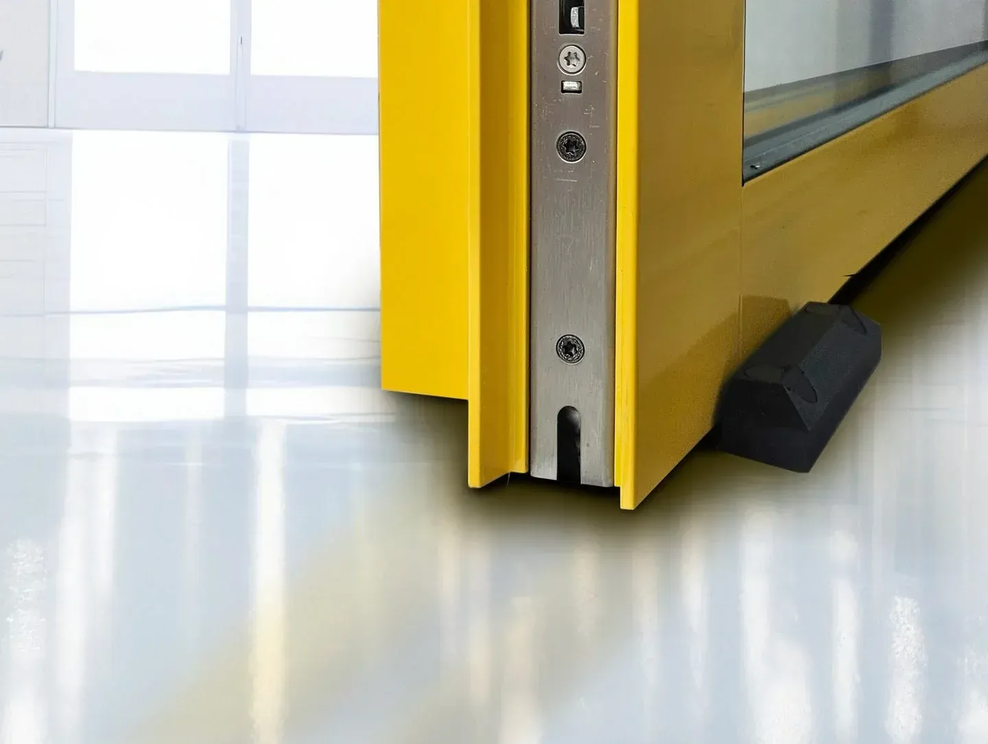 Una puerta amarilla con un tapón de goma en el suelo.