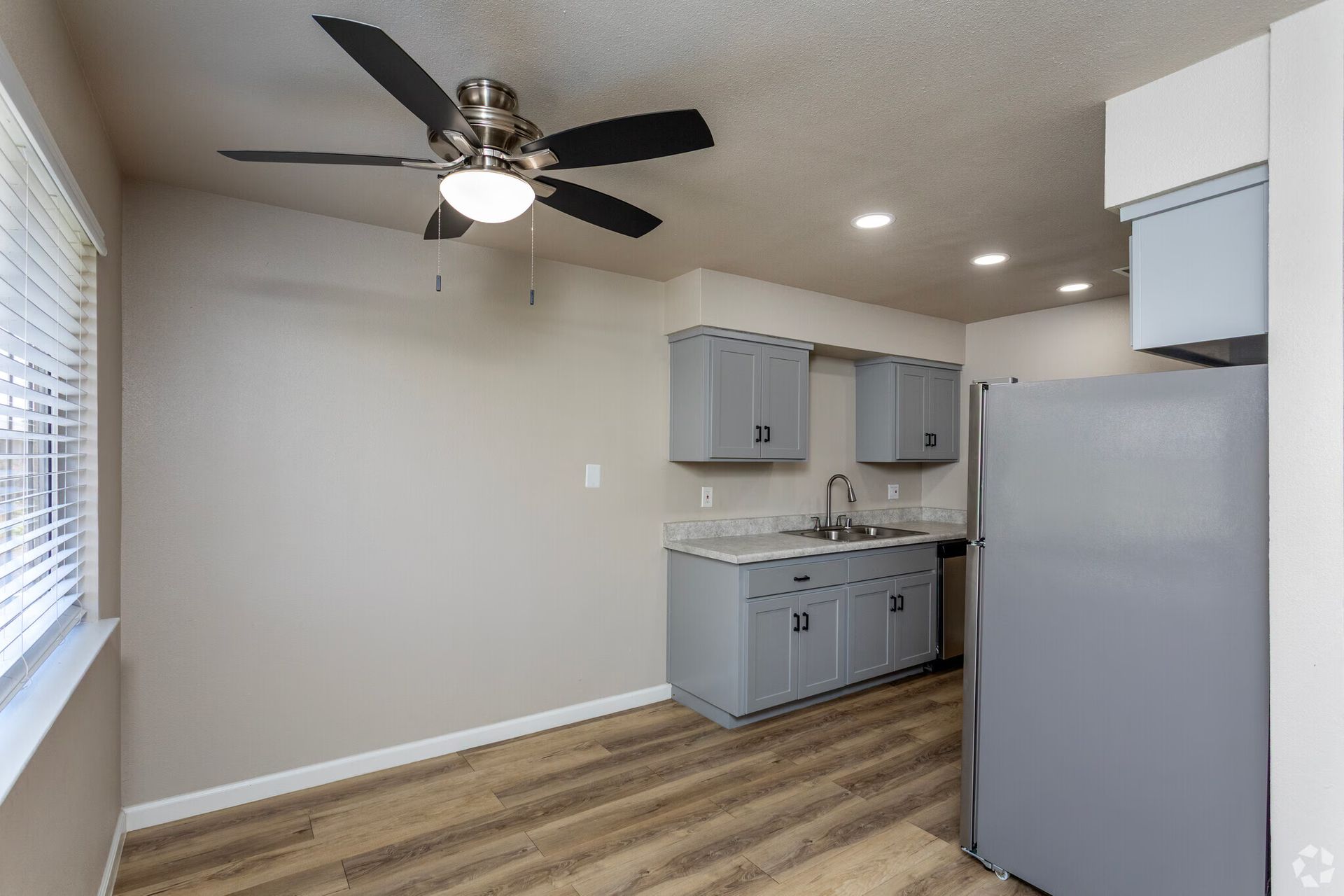 Kitchen with gray cabinets, stainless steel sink, and light wood-look flooring.