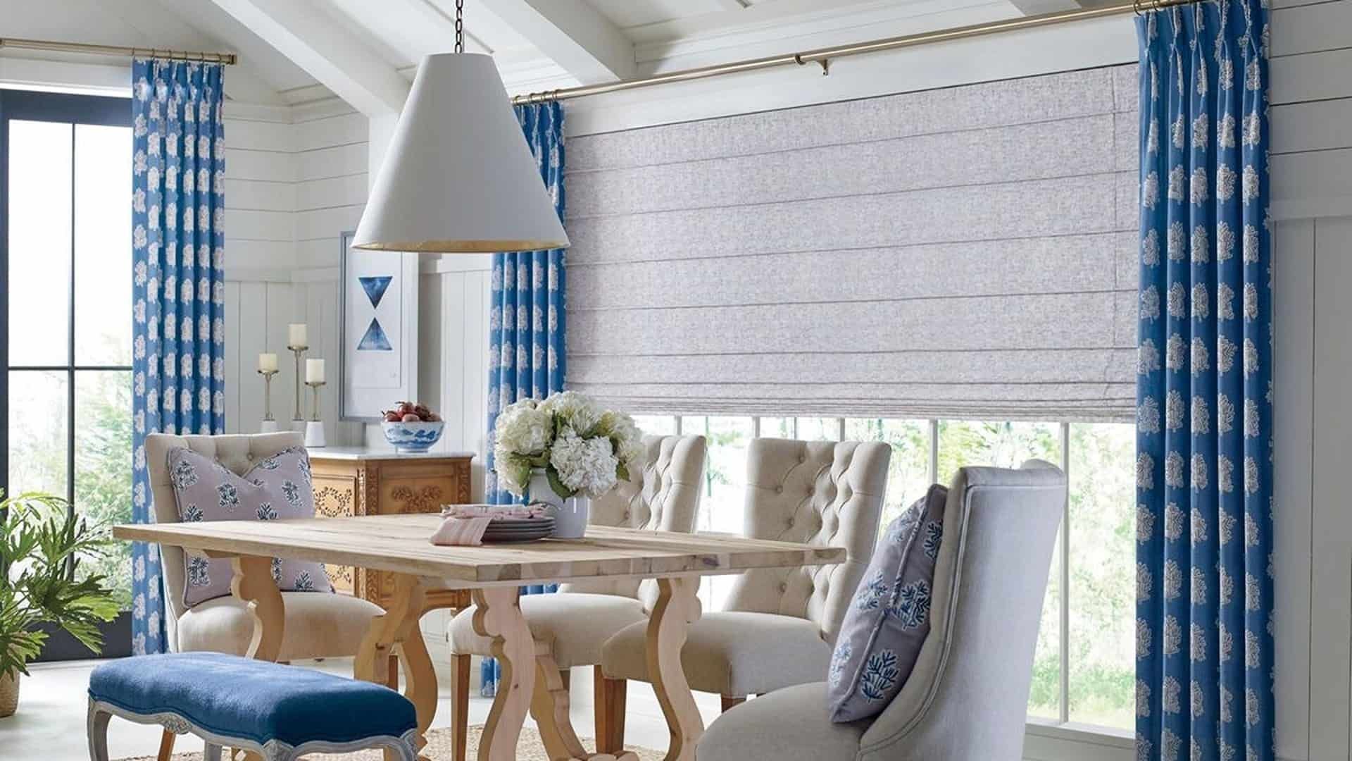 An open room with Hunter Douglas Roman Shades and a dining table