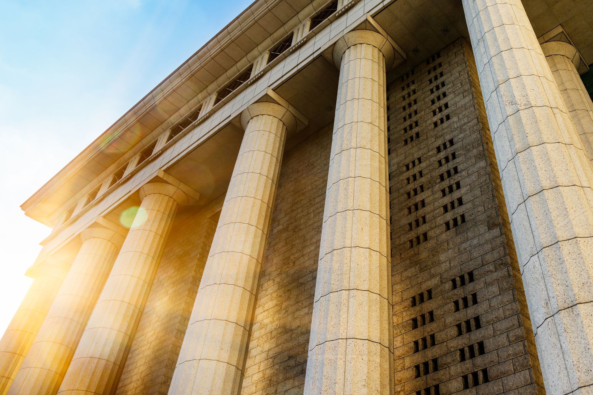 The sun is shining through the columns of a building.