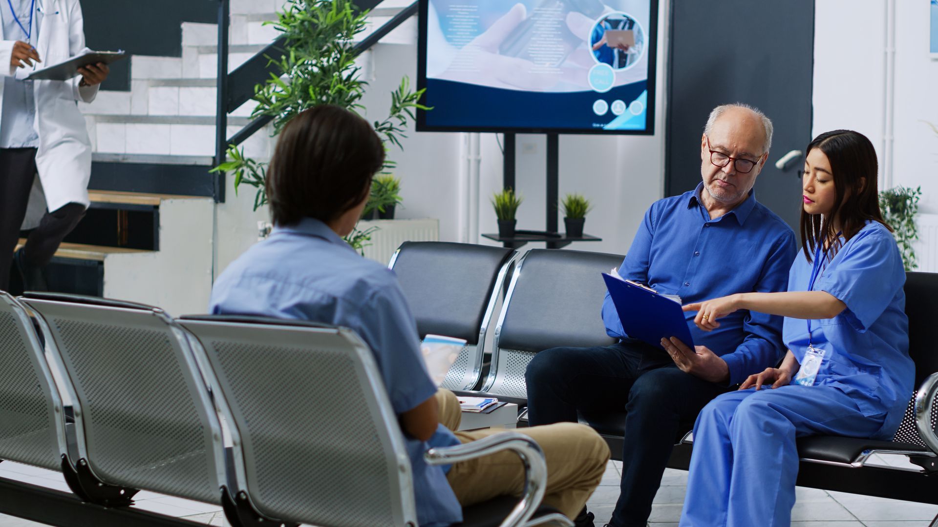 A group of people are sitting in a waiting room talking to a doctor.