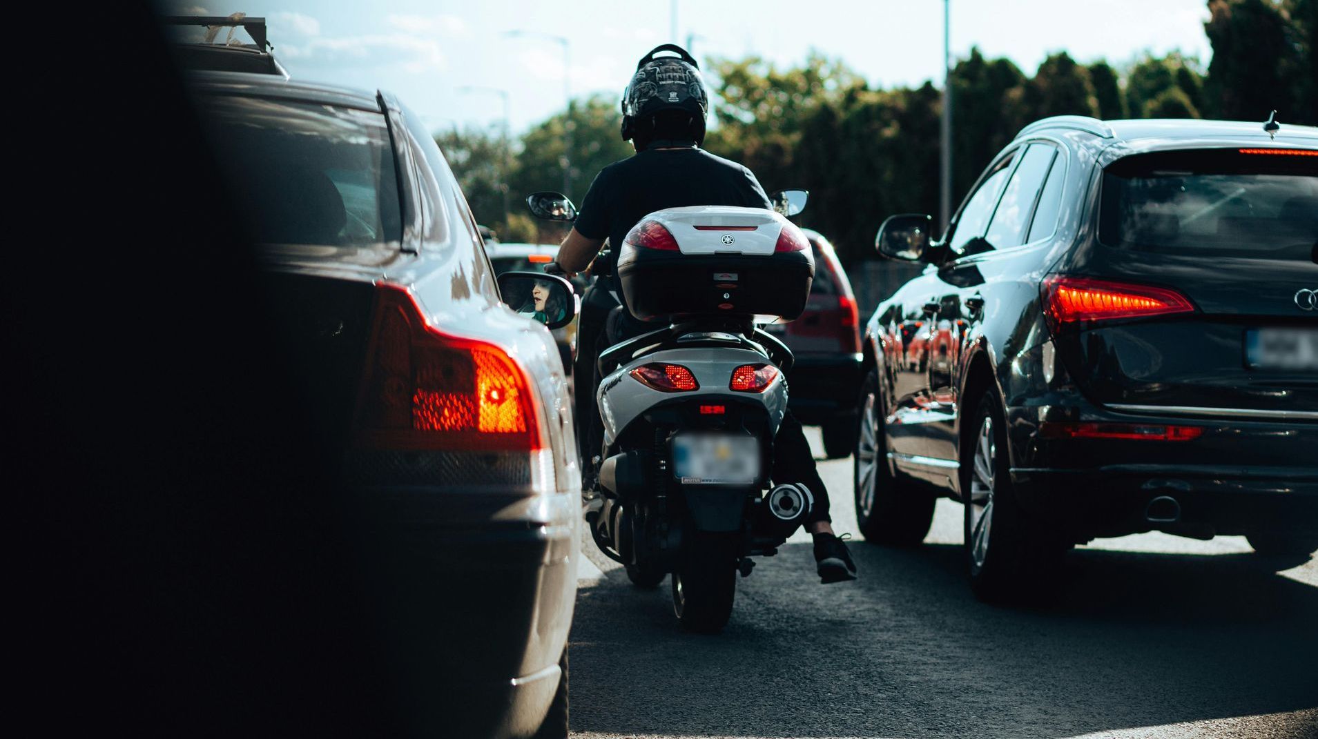 A man is riding a motorcycle in a traffic jam.