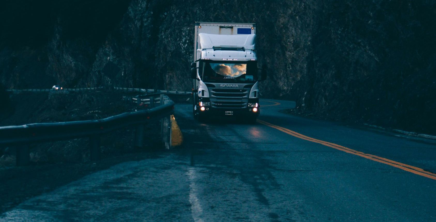 A truck is driving down a curvy road at night.