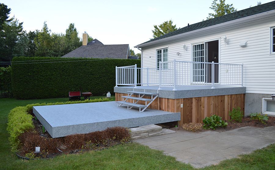 Une maison blanche avec une terrasse et des escaliers couverts d'une membrane de PVC devant elle