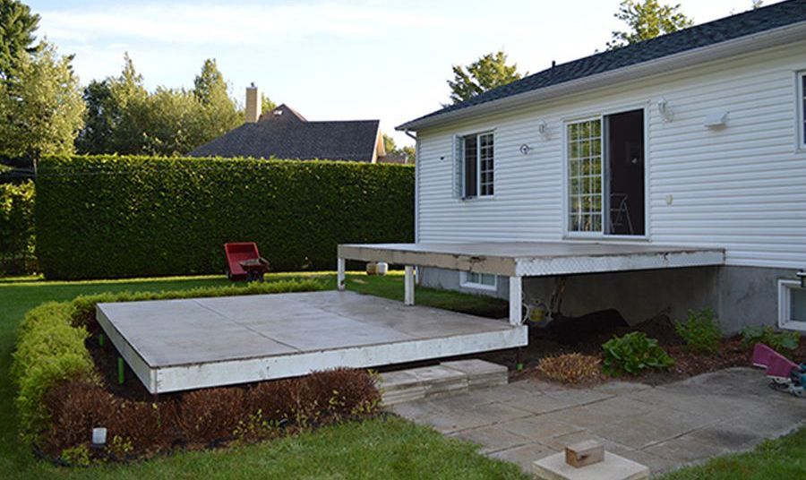 Une maison blanche avec une terrasse en bois devant elle