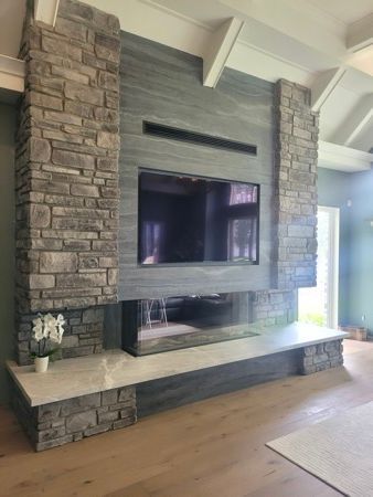 Un salon avec une cheminée et une télévision écran plat au mur.