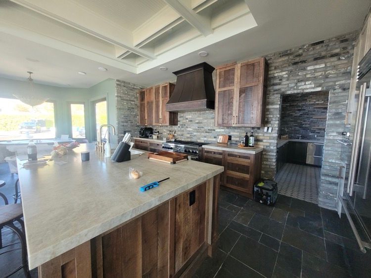 Une cuisine avec armoires en bois, comptoirs en granit, électroménagers en acier inoxydable et un grand îlot.