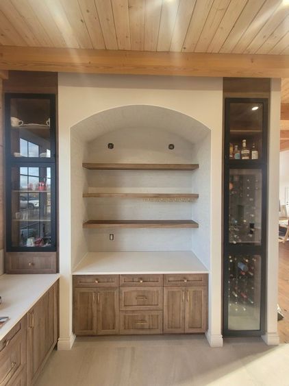 Une cuisine avec des armoires et des étagères en bois et une cave à vin