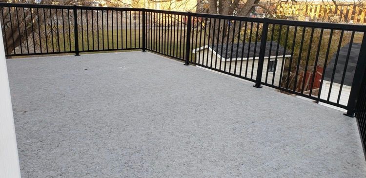 Un balcon couvert de pvc avec une balustrade noire.