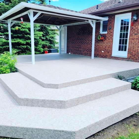 Un patio avec trois paliers et un auvent devant une maison en brique