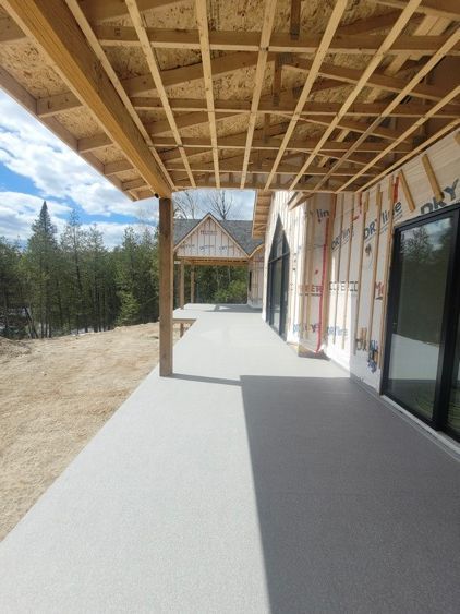 Une maison en construction avec un porche couvert de membrane de pvc et beaucoup de fenêtres.