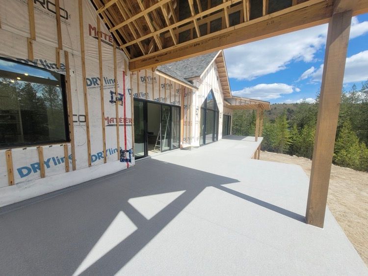 Une maison est en construction avec un grand patio devant elle.