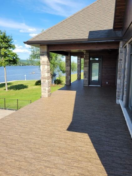 Une grande maison avec un grand porche donnant sur un lac.