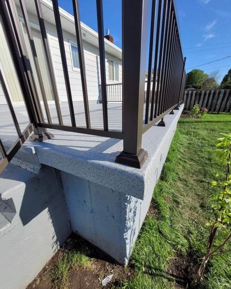 Une terrasse avec une balustrade et une fondation en béton devant une maison.