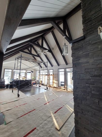 Une grande pièce avec un plafond voûté et une section de mur de briques.