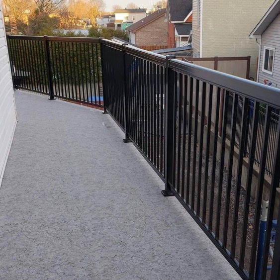 Un balcon avec une balustrade noire et un sol recouvert de membrane de pvc.
