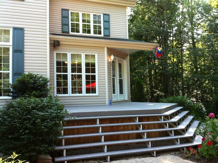 Une maison avec un porche et des très grands escaliers devant.