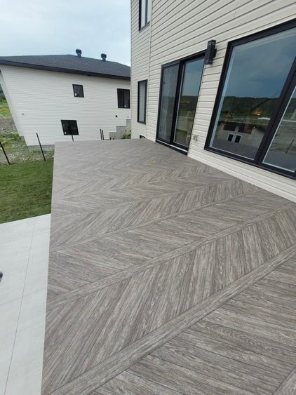 Un grand patio avec un plancher en membrane de pvc et une maison en arrière-plan.