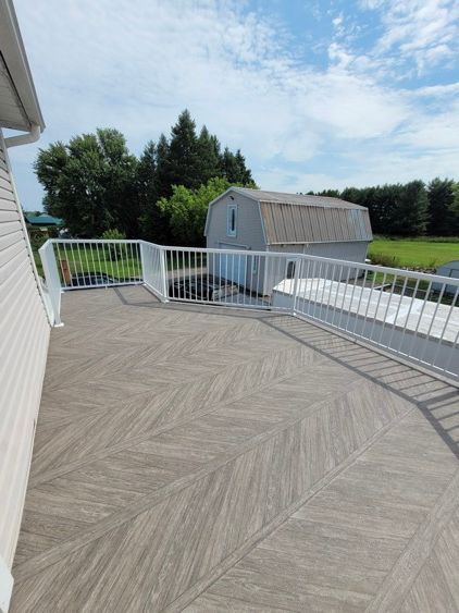 Une grande terrasse avec une balustrade blanche et une grange en arrière-plan.
