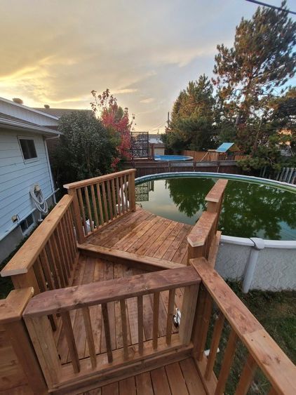 Une terrasse en bois avec des escaliers menant à une piscine.