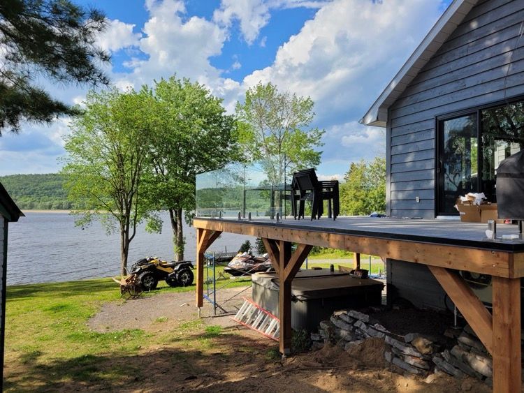 Une maison avec une grande terrasse donnant sur un lac.