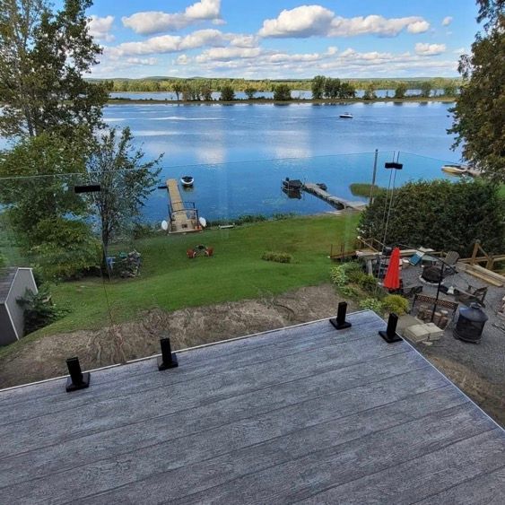 Une vue sur un lac depuis une terrasse avec une balustrade en verre.