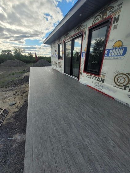 Une maison est en construction avec une grande terrasse devant elle.