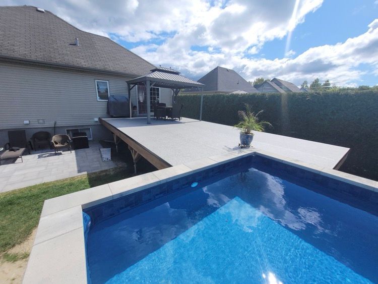 Il y a une grande piscine dans l'arrière-cour d'une maison à coté d'une grande terrasse en membrane de pvc.