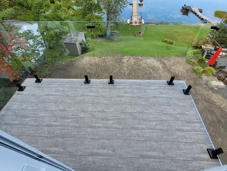 Une vue aérienne d'une terrasse avec une balustrade en verre donnant sur un lac.