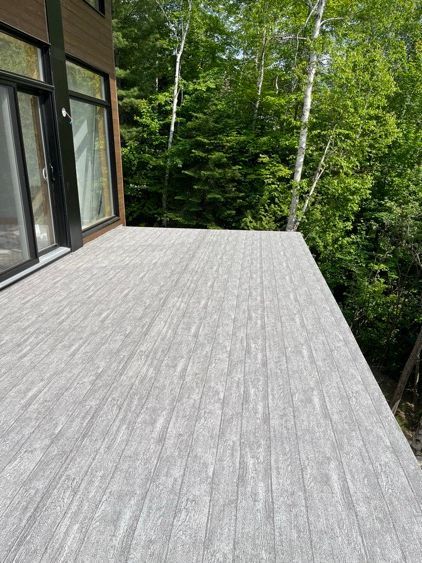 Une grande terrasse avec beaucoup de fenêtres et d'arbres en arrière-plan.