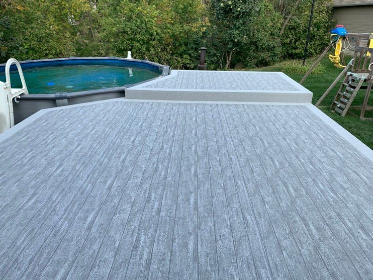 Un patio en membrane de pvc grise avec une piscine en arrière-plan.