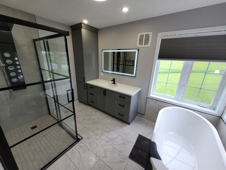 Une salle de bain avec baignoire, lavabo, douche vitrée et miroir.