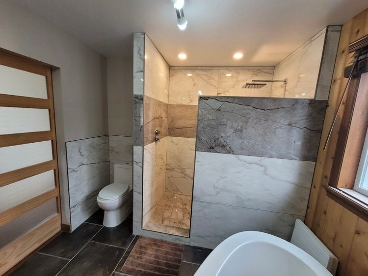 Une salle de bain avec baignoire, toilette, douche ouverte et fenêtre.