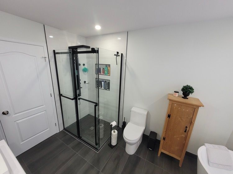 Une salle de bain avec toilette, douche et meuble de rangement en bois.