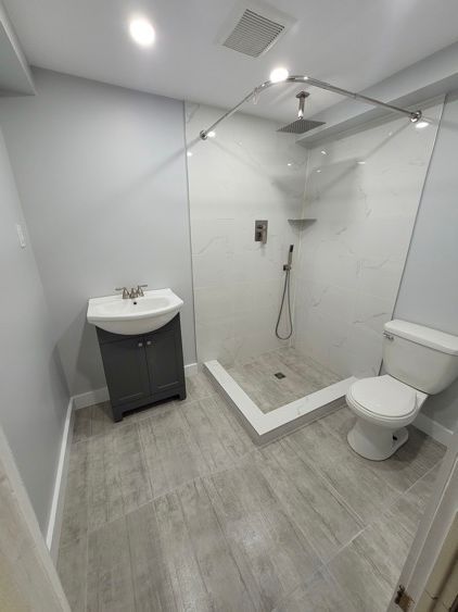 Une salle de bain avec lavabo, toilette et douche à l'italienne.