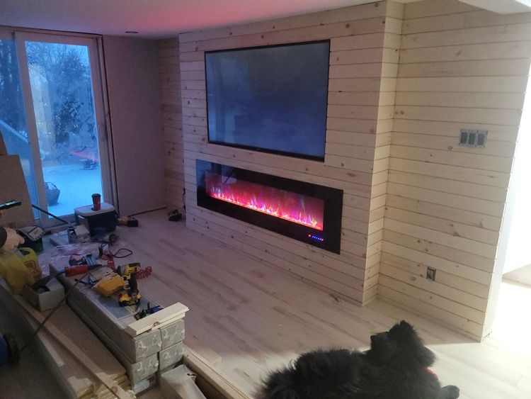 Un chien est allongé dans un salon avec une cheminée et une télévision.