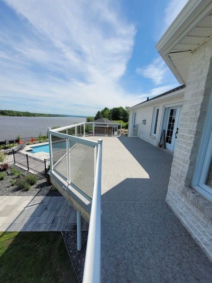 Une grande terrasse avec vue sur un lac et une piscine.