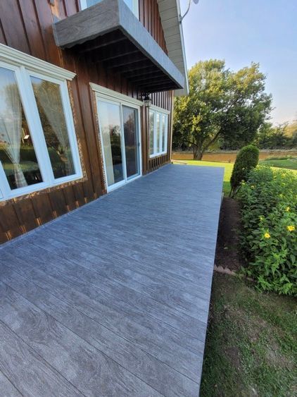 Il y a une grande terrasse devant une maison avec beaucoup de fenêtres.