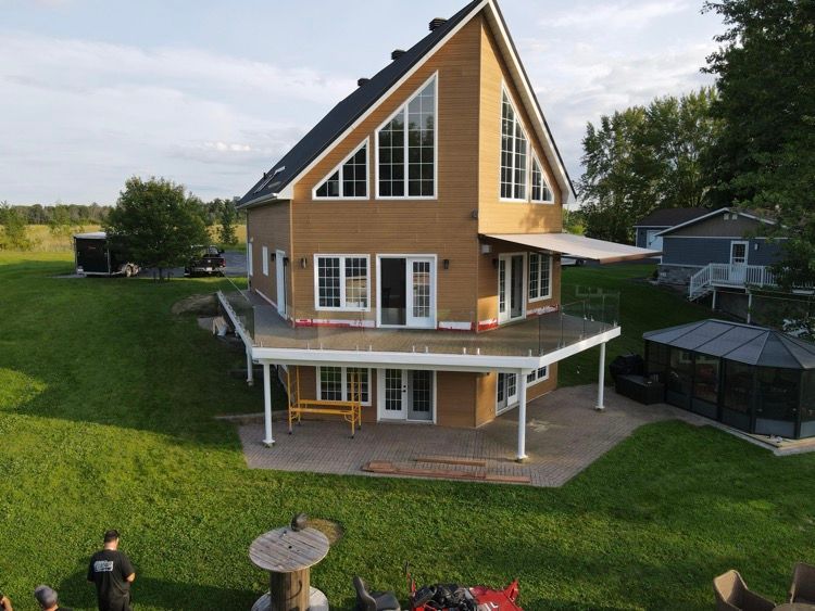 Une vue aérienne d'une maison avec une grande terrasse avec rampe vitrée.