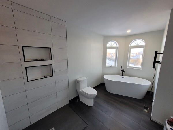 Une salle de bain blanche avec baignoire, toilettes et douche.