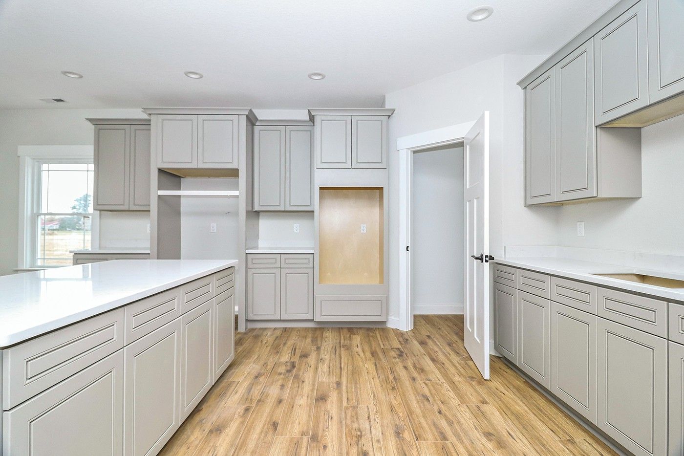 An empty kitchen with gray cabinets and wooden floors.