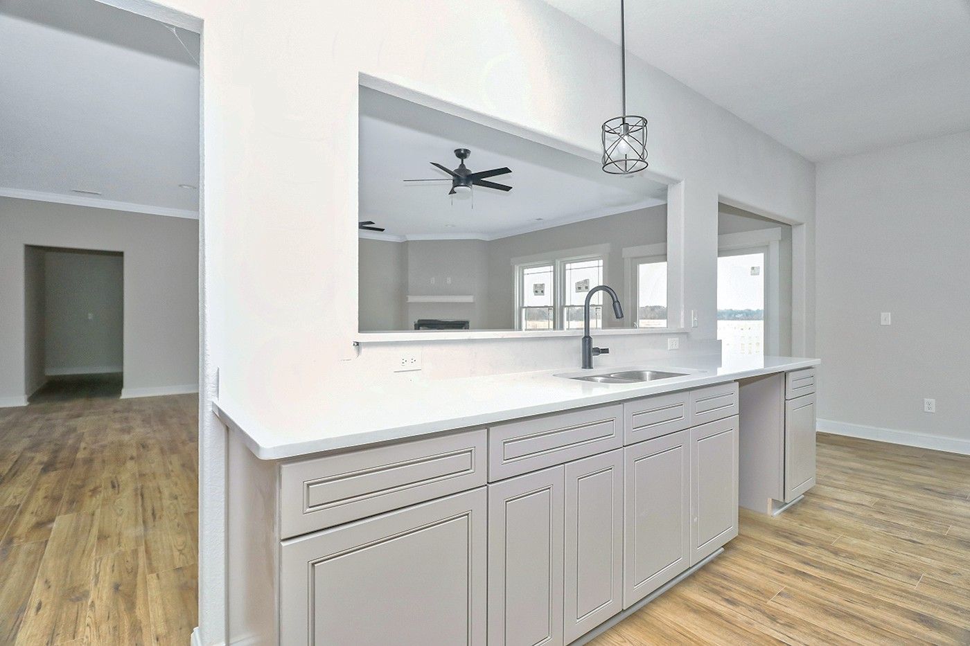 A kitchen with white cabinets , a sink and a ceiling fan.