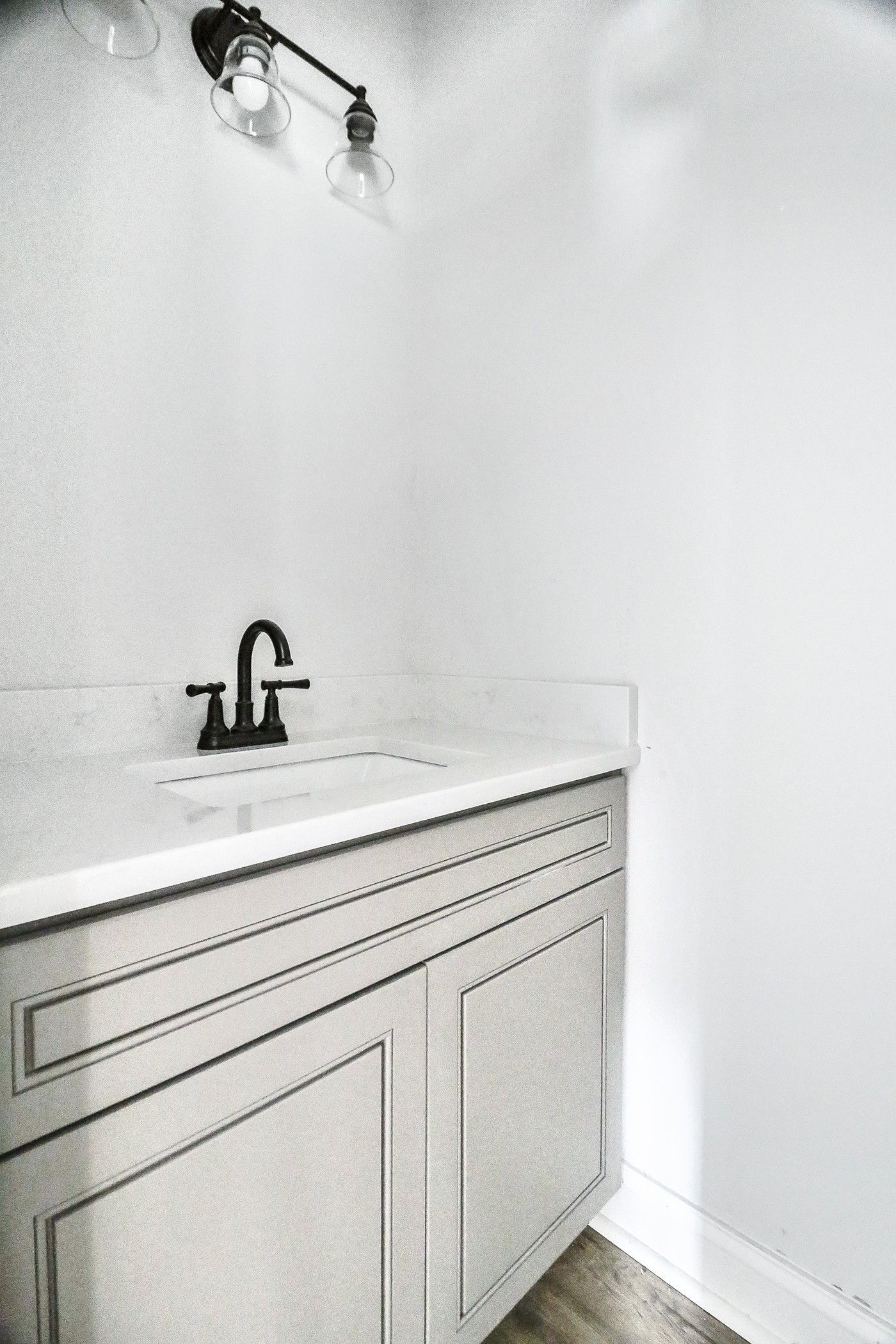 A bathroom with a sink and a light on the wall.