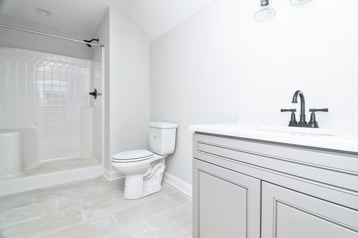A bathroom with a toilet , sink and shower.